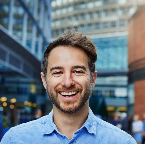 Forretningsmann som smiler selvsikkert, og representerer profesjonalitet, suksess og en positiv arbeidsinnstilling